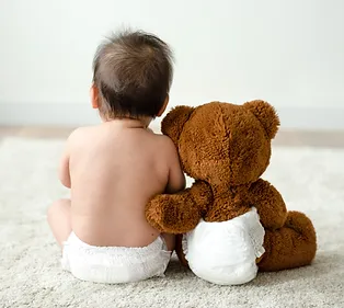 baby sitting next to teddy bear