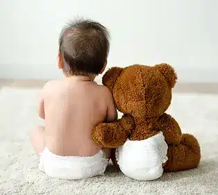 baby sitting next to teddy bear